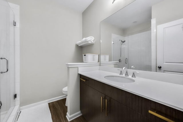 bathroom with hardwood / wood-style flooring, vanity, a shower with shower door, and toilet