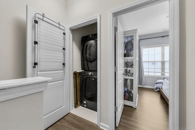 washroom with stacked washer / drying machine and dark hardwood / wood-style floors