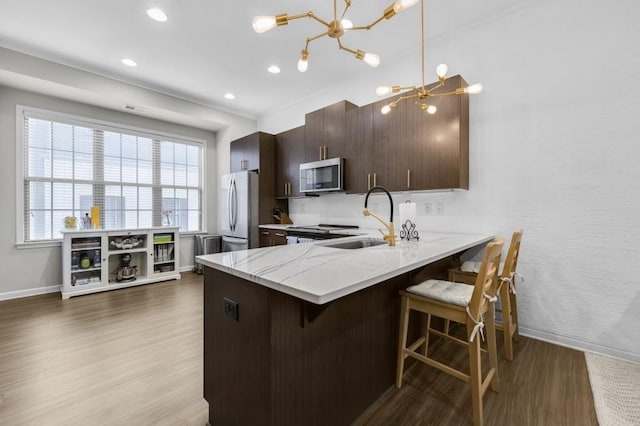 kitchen featuring sink, a breakfast bar area, light wood-type flooring, appliances with stainless steel finishes, and kitchen peninsula