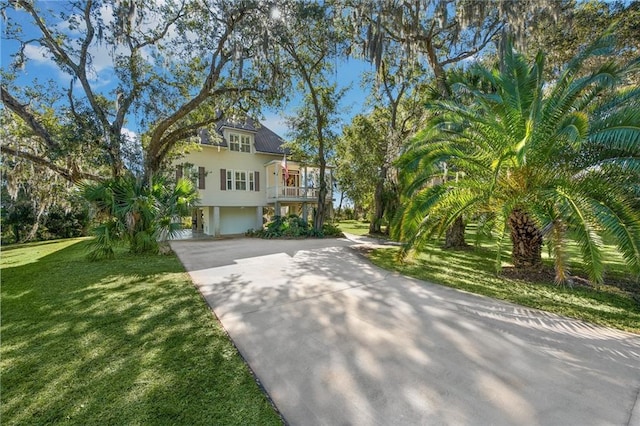 coastal inspired home with a front yard, driveway, stairway, and stucco siding