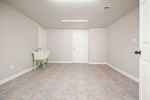 empty room featuring baseboards, stone finish floor, and visible vents