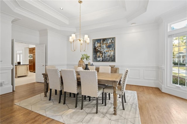 dining area with a tray ceiling, a wealth of natural light, and light hardwood / wood-style floors