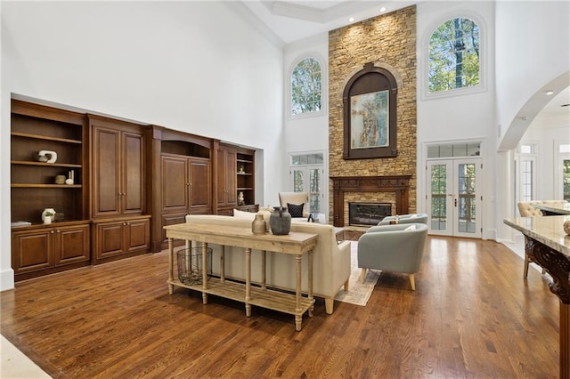 living room with a towering ceiling, a healthy amount of sunlight, and french doors