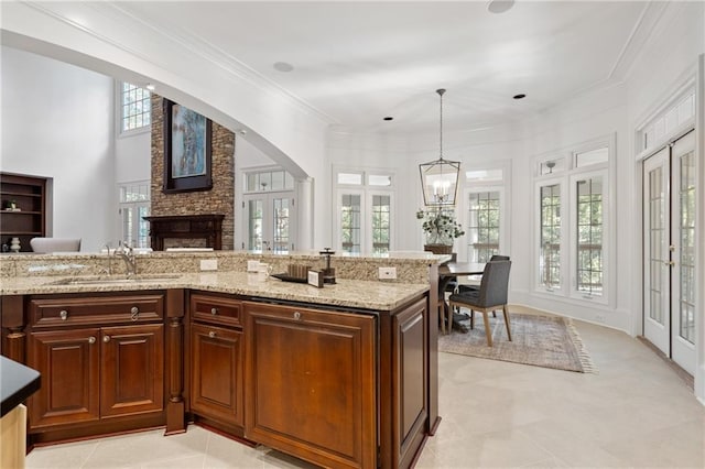 kitchen featuring a stone fireplace, sink, a wealth of natural light, and decorative light fixtures