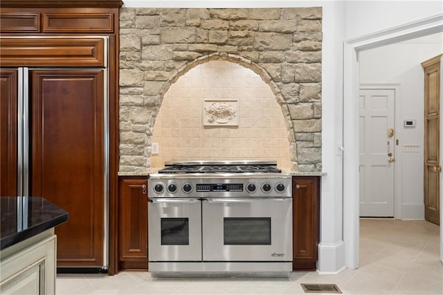 kitchen featuring high end stainless steel range, light stone countertops, and light tile patterned floors