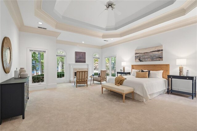 carpeted bedroom featuring a tray ceiling, ceiling fan, and crown molding