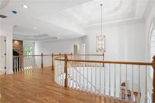 hall featuring a tray ceiling, hardwood / wood-style flooring, and ornamental molding