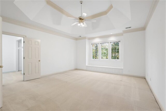 carpeted empty room with ceiling fan, a tray ceiling, and ornamental molding