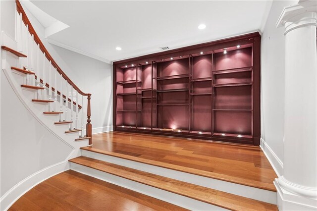 interior space with wood-type flooring, ornate columns, and crown molding