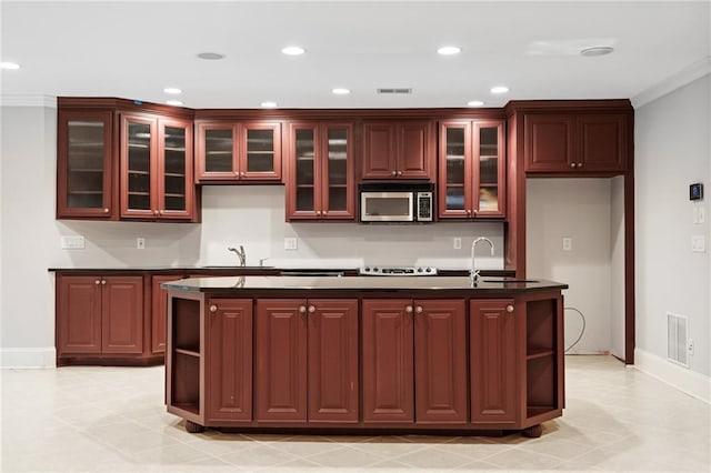 kitchen with stove, sink, an island with sink, and ornamental molding