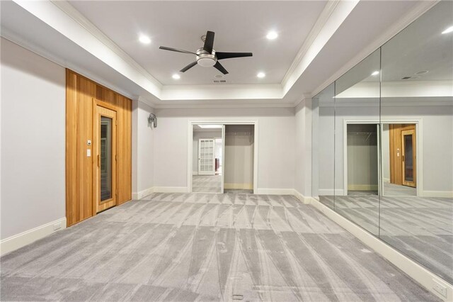 carpeted spare room with a tray ceiling, ceiling fan, and crown molding