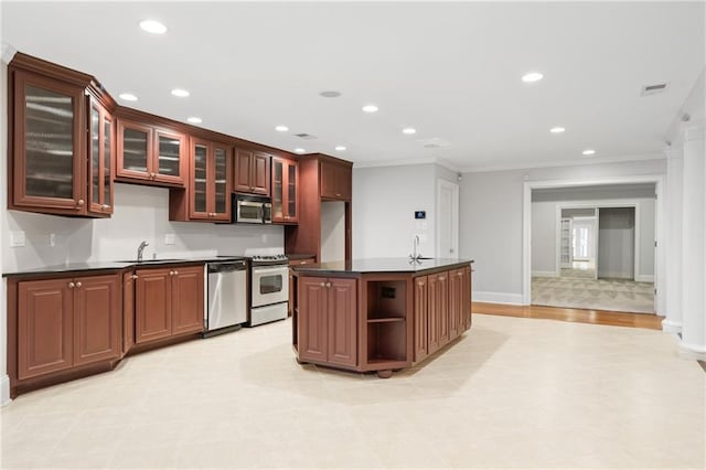 kitchen with crown molding, appliances with stainless steel finishes, a center island with sink, and sink