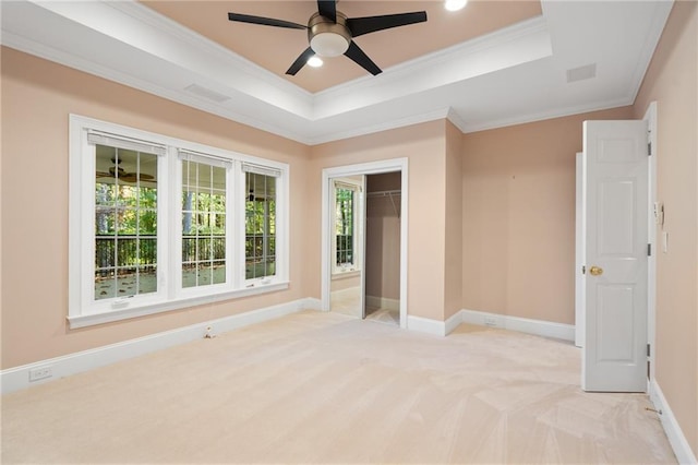 unfurnished bedroom with light colored carpet, ornamental molding, ceiling fan, a raised ceiling, and a closet