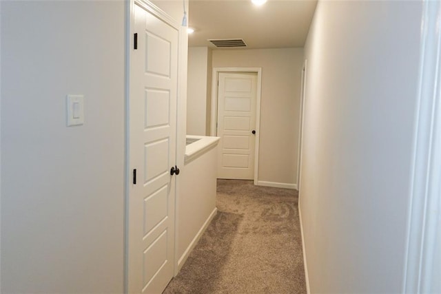 corridor featuring light colored carpet, visible vents, and baseboards