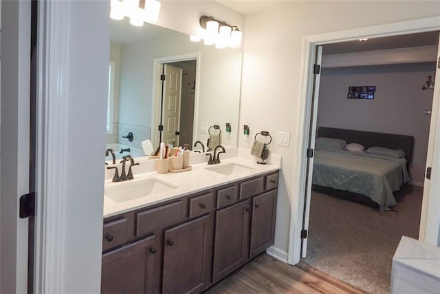 ensuite bathroom featuring a sink, double vanity, wood finished floors, and ensuite bath