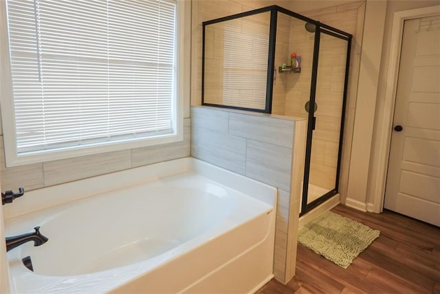 full bath featuring a garden tub, a shower stall, and wood finished floors