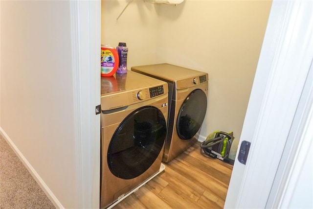 clothes washing area with laundry area, independent washer and dryer, baseboards, and wood finished floors