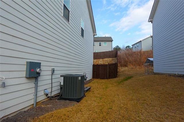 view of side of property featuring a yard, fence, and central air condition unit