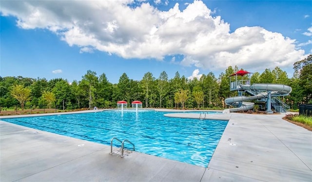 community pool featuring a water slide, a patio area, and fence