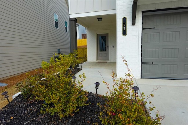 property entrance featuring board and batten siding, brick siding, and a garage