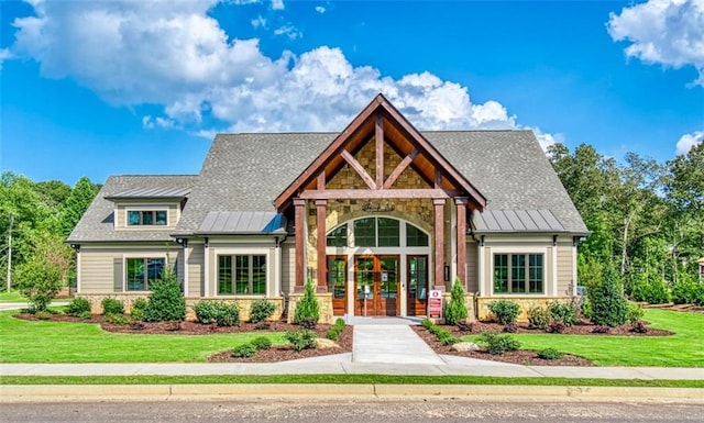 view of front of property with a standing seam roof, stone siding, metal roof, and french doors