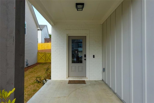 doorway to property with brick siding, fence, and a patio