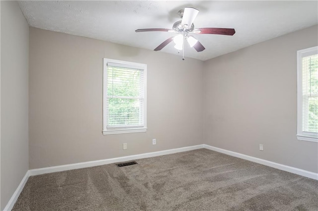 carpeted empty room with baseboards, visible vents, and ceiling fan