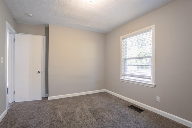 carpeted empty room with a textured ceiling, visible vents, and baseboards
