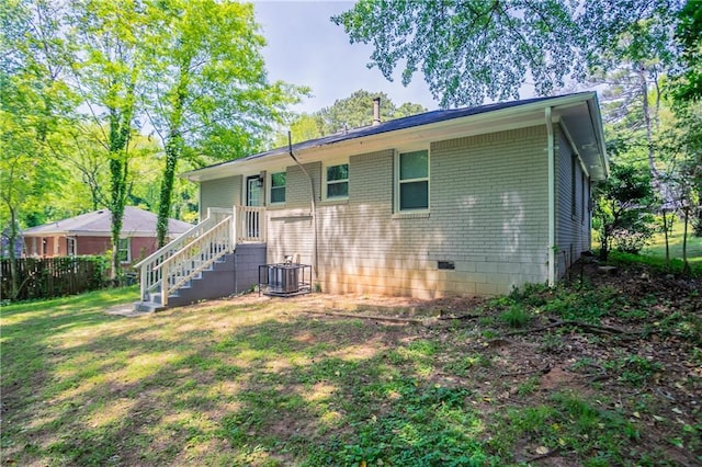 back of house with fence, central AC unit, a yard, and brick siding