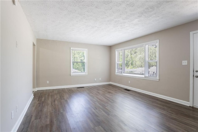 unfurnished living room featuring baseboards, a wealth of natural light, a textured ceiling, and dark wood-style flooring