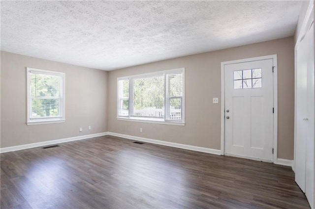 foyer entrance with dark wood-style floors, visible vents, a healthy amount of sunlight, and a textured ceiling