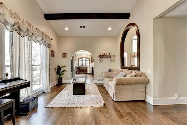 living room with arched walkways, wood finished floors, visible vents, and baseboards