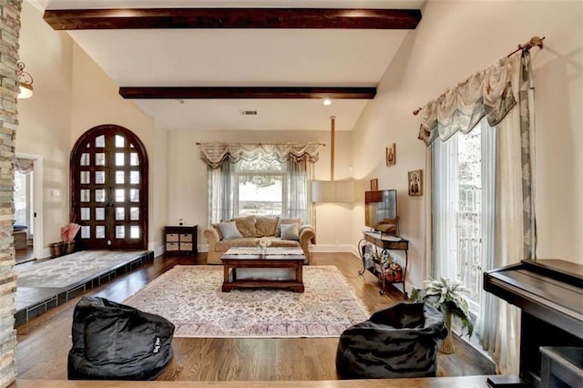 living room with vaulted ceiling with beams, wood finished floors, and baseboards