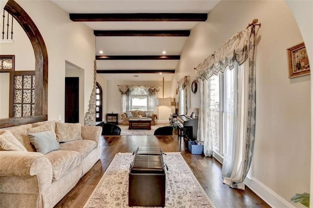 living room featuring dark wood-style floors, beamed ceiling, and baseboards