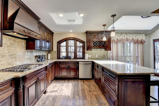 kitchen featuring hanging light fixtures, appliances with stainless steel finishes, a peninsula, and visible vents