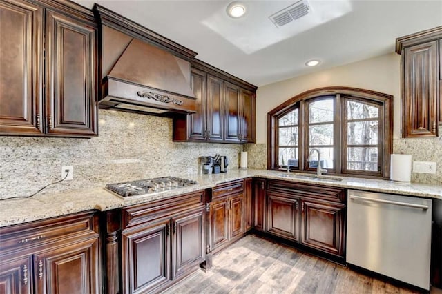 kitchen with tasteful backsplash, visible vents, appliances with stainless steel finishes, custom exhaust hood, and a sink