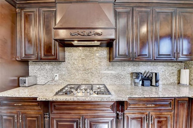 kitchen featuring tasteful backsplash, dark brown cabinets, premium range hood, and stainless steel gas stovetop