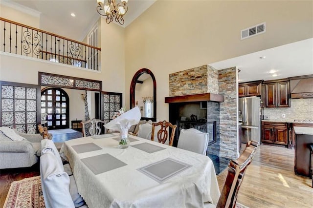 dining space featuring arched walkways, recessed lighting, a notable chandelier, visible vents, and light wood finished floors