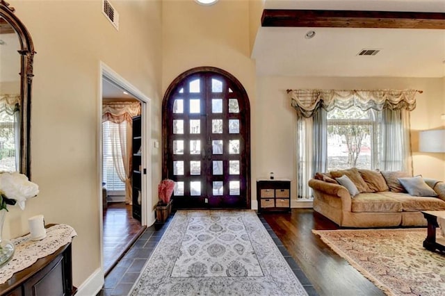 entryway featuring baseboards, visible vents, dark wood finished floors, and beamed ceiling