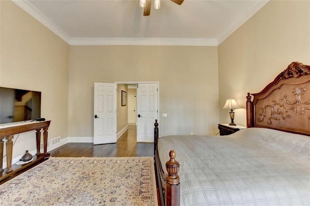 bedroom with crown molding, visible vents, dark wood finished floors, and baseboards