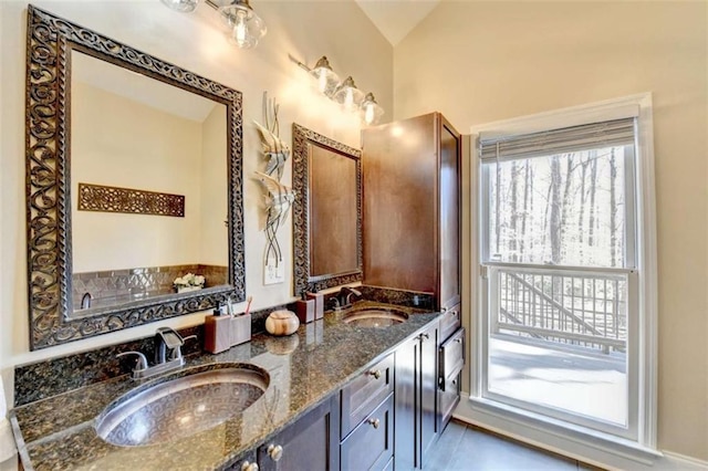 full bathroom featuring tile patterned floors, vaulted ceiling, a sink, and double vanity