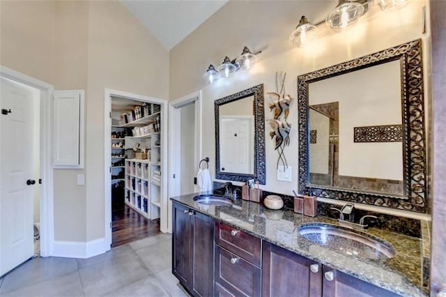 bathroom with double vanity, tile patterned flooring, a sink, and lofted ceiling