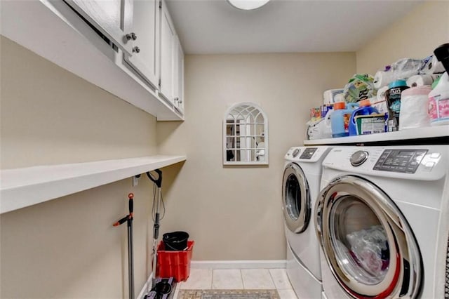 laundry area with light tile patterned floors, washing machine and clothes dryer, cabinet space, and baseboards