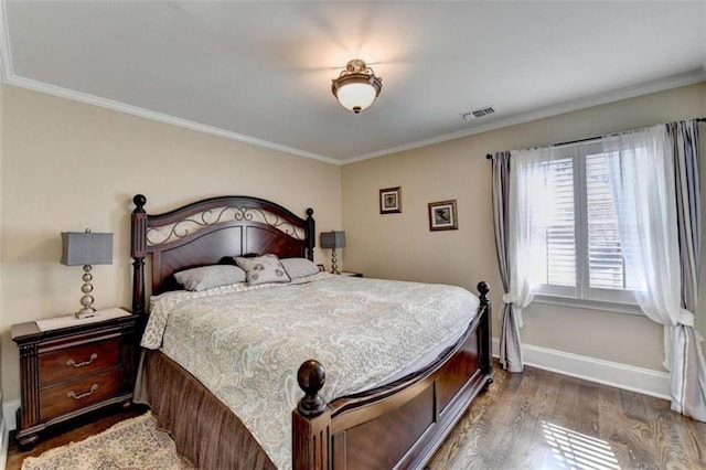 bedroom with ornamental molding, visible vents, baseboards, and wood finished floors