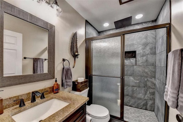 bathroom featuring toilet, a stall shower, vanity, and recessed lighting