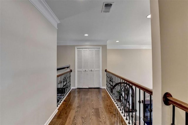 corridor featuring recessed lighting, wood finished floors, visible vents, baseboards, and crown molding