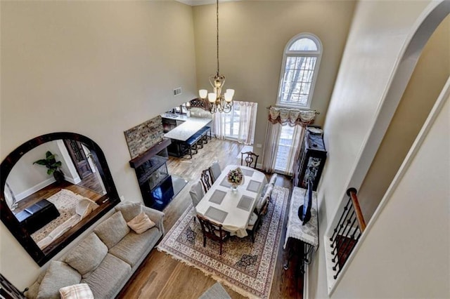 living area with arched walkways, a notable chandelier, a towering ceiling, and wood finished floors