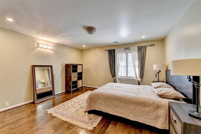 bedroom featuring visible vents, baseboards, wood finished floors, and recessed lighting