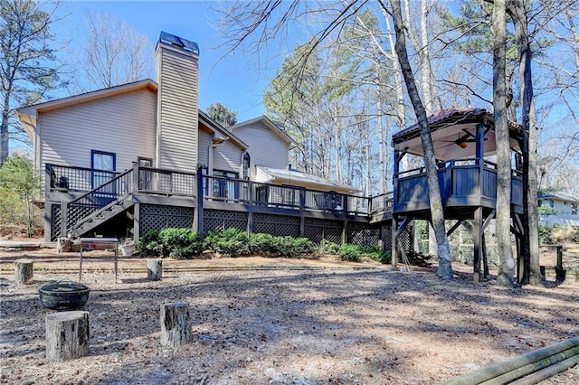 rear view of house with a chimney, a wooden deck, and stairs