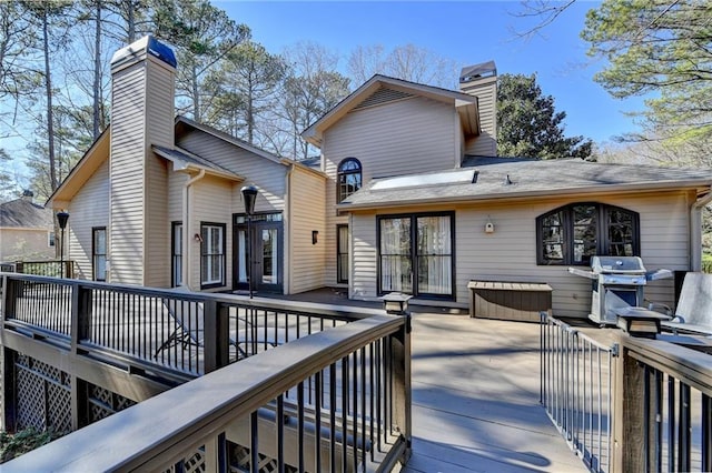 rear view of property with a deck, a chimney, and a jacuzzi